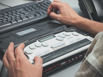 A pair of hands next to a keyboard and an attachment with large buttons